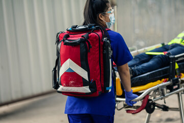 Selective focus, Medical bag on back of paramedic female during move worker is patient lying on...