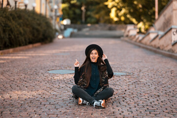 Fototapeta premium Young woman sitting at city show finger up, new idea
