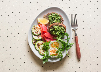 Delicious breakfast, snack - boiled egg, smoked salmon, grilled zucchini, avocado toast on a light background, top view