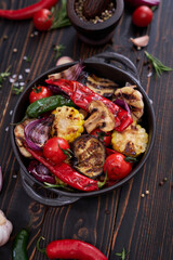 Grilled vegetables in black ceramic plate on table at domestic kitchen