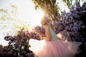 Portrait of a beautiful girl with a wreath on her head made of a purple flowers. A woman dressed...