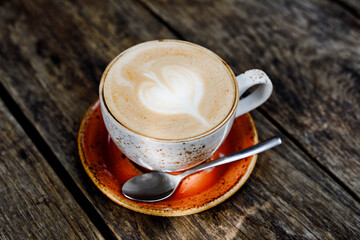 Cup of flat white coffee on a wooden table in an outdoor cafe or restaurant. Rustical style.