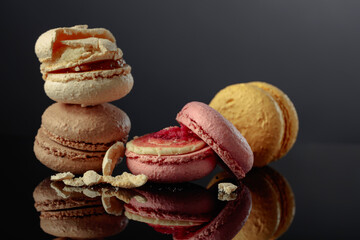 Delicious colorful macaroons on a black reflective background.