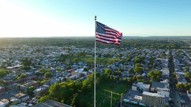 American flag waves over American city during sunset light.