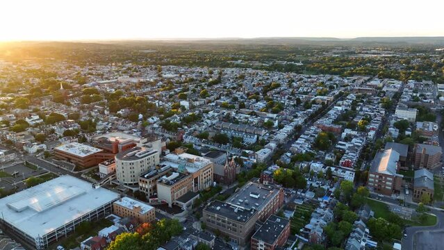 American city aerial orbit at sunset. Allentown Pennsylvania establishing shot above residential homes.