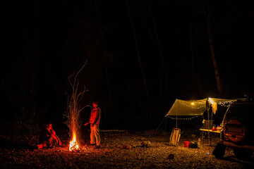 A couple at the campfire in autumn forest in the night.