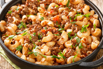 Hamburger Macaroni with with vegetables and cheese closeup in the pan on the wooden table. Horizontal