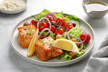 Dish with baked Salmon steak fillet with fresh green salad with vegetables, tomatoes, onion, lemon in a plate. Keto diet concept healthy food, close up.