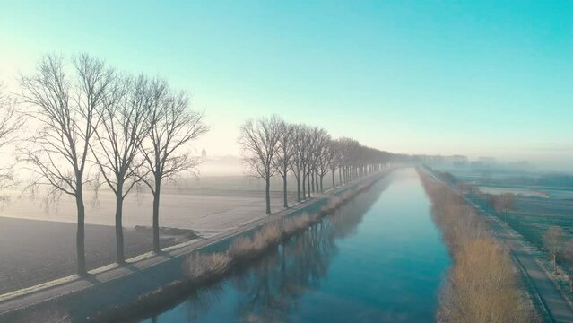Drone shot dolly sideways above the Scheldt river next Escanaffles in the morning with smog and nice light