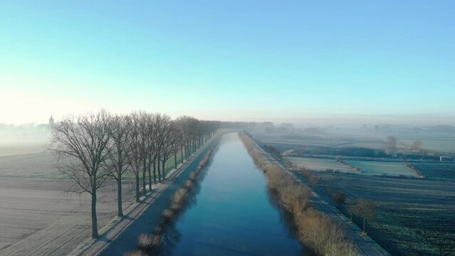 Drone shot dolly forward above de water on the Scheldt river next Escanaffles in the morning with smog and nice light