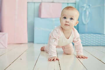 A baby lies on a soft surface in a bright room, dressed in pink clothing. The concept of childhood