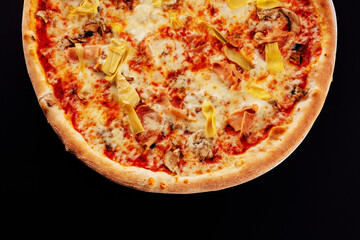 italian pizza with sliced ham and artichokes on black background