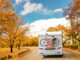 ccaravan car on the road in autumn with oak trees yellow leaves  in autumn season travelling...