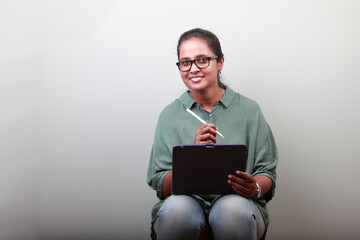 Woman of Indian ethnicity holding tablet phone and with a smiling face 