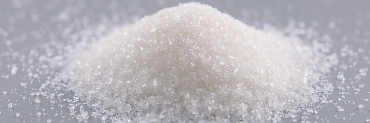 Pile of sugar crystals on grey surface, focus on heap of sweet powder to add in dishes