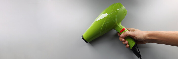 Brand new hairdryer model, bright green device for drying hair in hand
