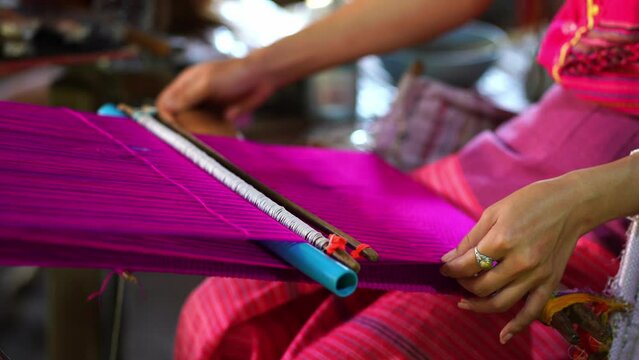Close up hands of woman weaving fabric a traditional loom