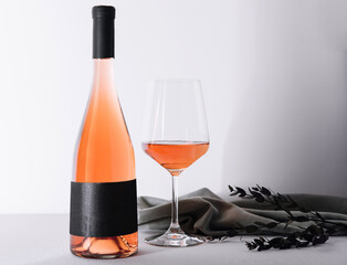Glass and bottle of rose wine on light background