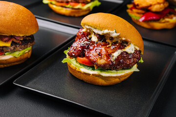 Appetizing crispy chicken burgers on black plates