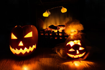 Two Jack-o'-lantern pumpkins and doll near burning fireplace in the dark
