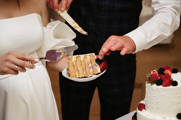 bride and groom cut a festive wedding cake into pieces with a knife