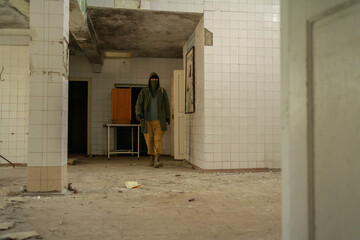 Young man walking in an abandoned building. wandering guy. man in a protective cloak with a hood....