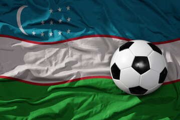 Naklejka premium vintage football ball on the waveing national flag of uzbekistan background. 3D illustration