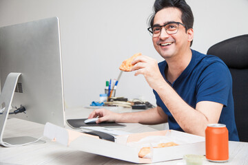 Man chilling have food while working and surfing the internet on his workstation.