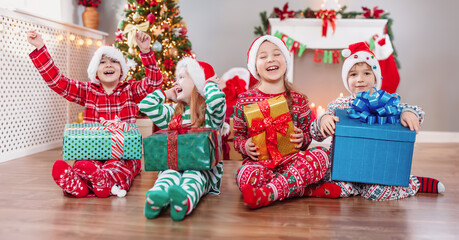 Group of children sitting on the floor indoors on Christmas morning.