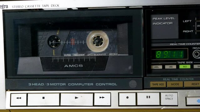 A man presses the stop button on a cassette recorder. Close-up playback of a vintage audio cassette.