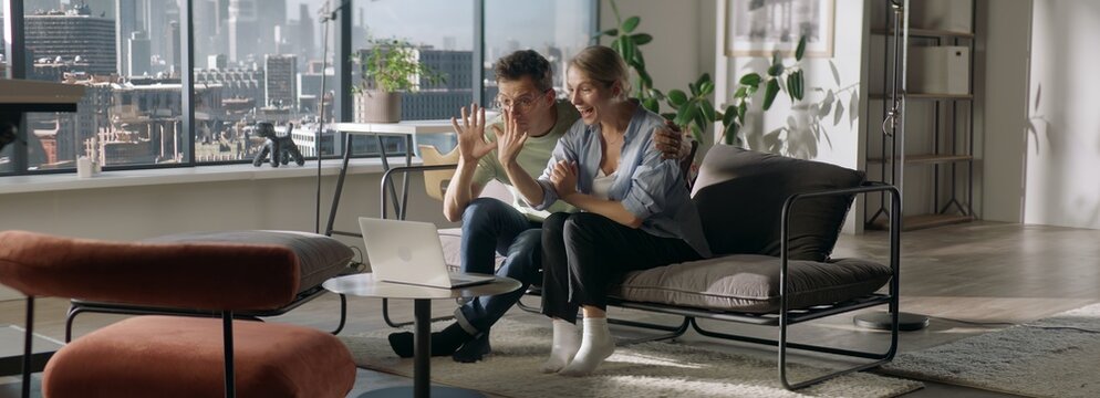 Young couple announcing their engagement to friends or family during video call, bride-to-be showing her ring finger to a phone camera
