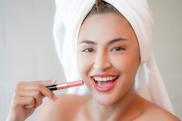 Young Women in white towel showing lipstick.