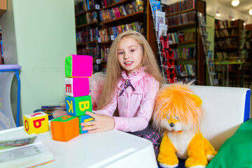 Cute little girl chooses a book in the library