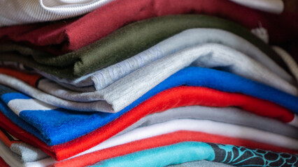 Stack of clothes in wardrobe. stack of colorful folded clothing items. household concept. Clean pile of laundry.