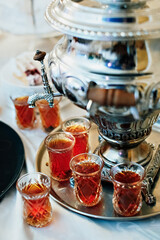 Tea in national Turkish glass glasses on a tray, next to the samovar