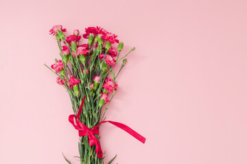 Red mini carnation and gift box. Concept of giving present at mother's day as surprise, flat lay, top view On pink Background