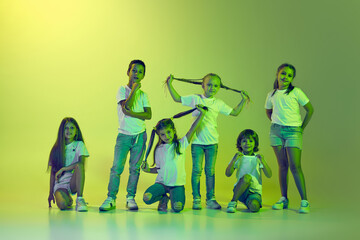 Group of children, little girls and boys in sportive casual style clothes dancing isolated on green...
