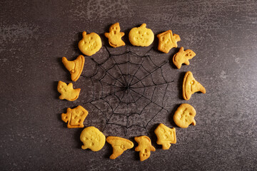 Halloween cookies laid out in a circle with cobwebs inside and a place for text on a gray background