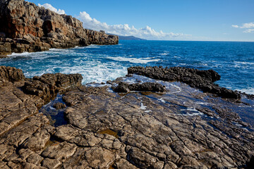 Fototapeta na wymiar Top view azure blue sea with waves beating on beach and rocks.
