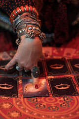 Arm of a woman tarot card reader full of rings and bracelets pointing to a tarot card lying face up...