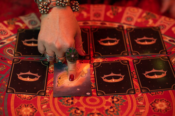 woman's hand with rings and accessories pointing to a tarot card that is face up on a table