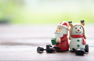 Santa and snowman sitting on the floor on green blurred background to created greeting card, Merry...