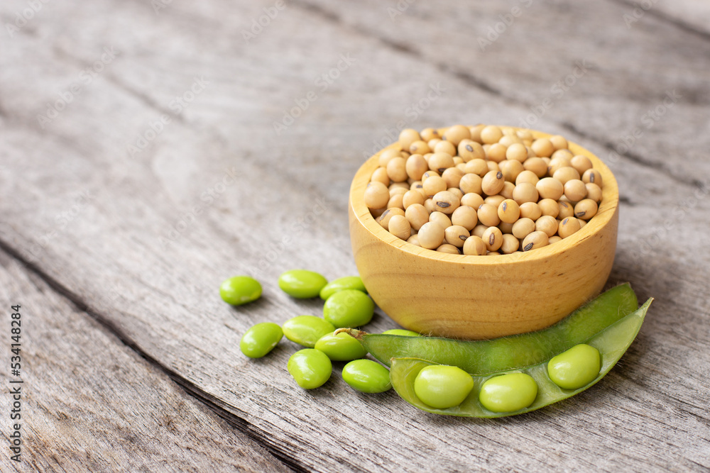 Sticker Green soybean in pod and dry soybeans in wooden bowl isolated on rustic wood table background. 