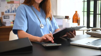 Healthcare costs and fees concept.Hand of smart doctor used a calculator and smartphone, tablet for medical costs at hospital in morning light. - Powered by Adobe