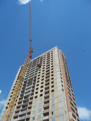 Crane and building under construction against blue sky