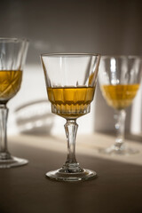 Alcohol drink in crystal glasses, sun light, shadows. Brandy or whiskey drink creative natural light.
