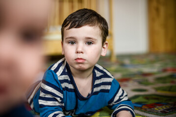 A little boy on the floor in the nursery.