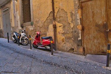 Red and white motor scooters parked next to a dilapidated wall captured in Naples, Italy
