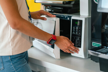 Female office worker in the office swithing on a microwave oven