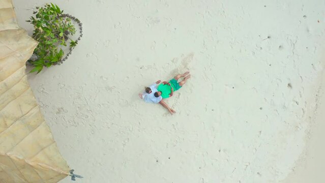Aerial view of a couple lying on the beach of Thinadhoo Island, Maldives.